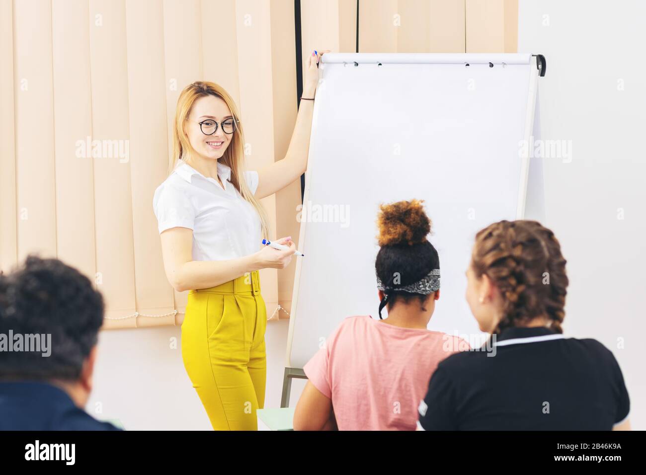 Cheerful modern young woman giving a presentation to international multiracial people Stock Photo