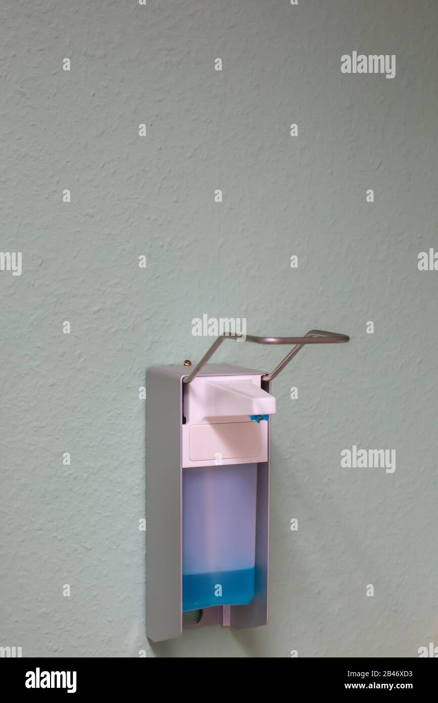 dispenser with a bottle of medical disinfectant hanging on a wall Stock Photo