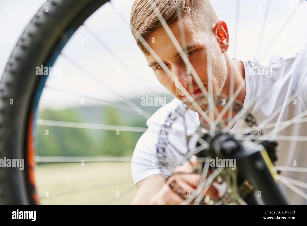 Teenage boy with flat tire while repairing bicycle in summer Stock Photo