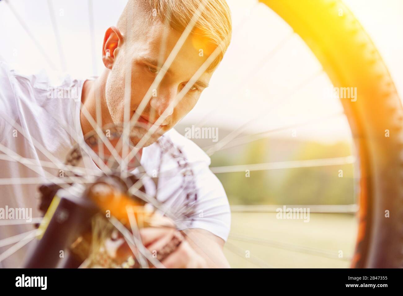 Man with bike breaks down on tire and repairs it in summer Stock Photo