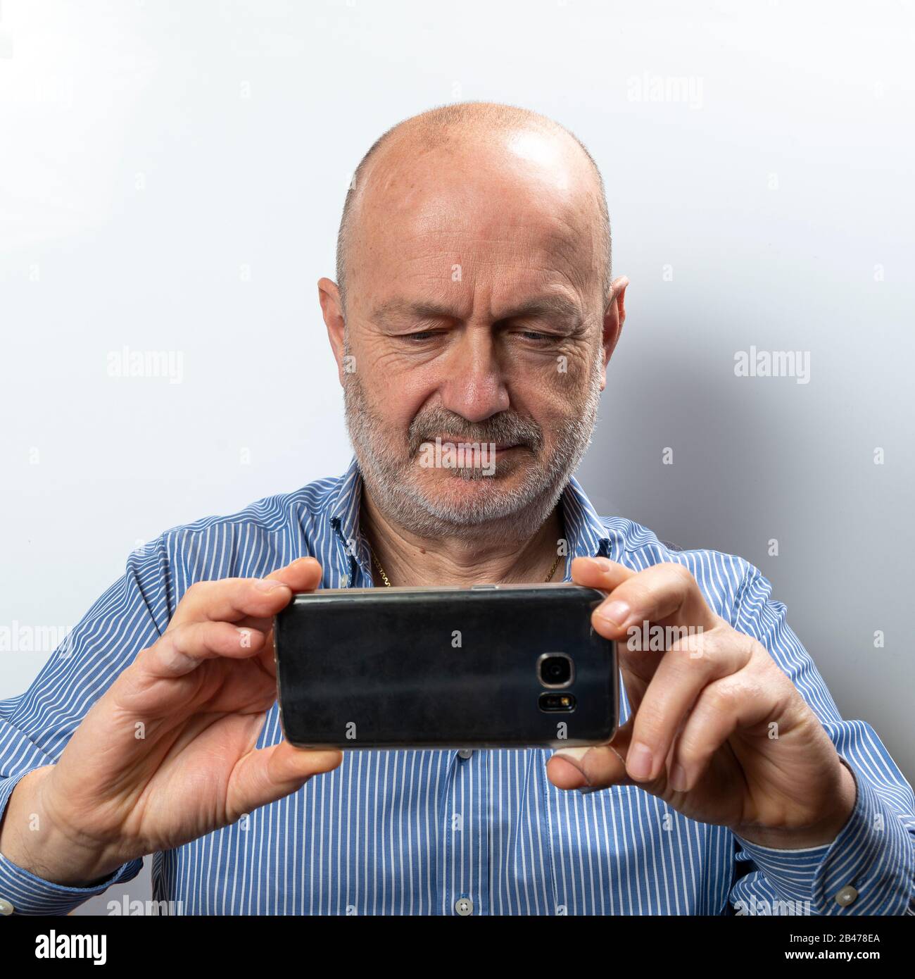 A middle-aged man takes a photograph with his cell phone Stock Photo