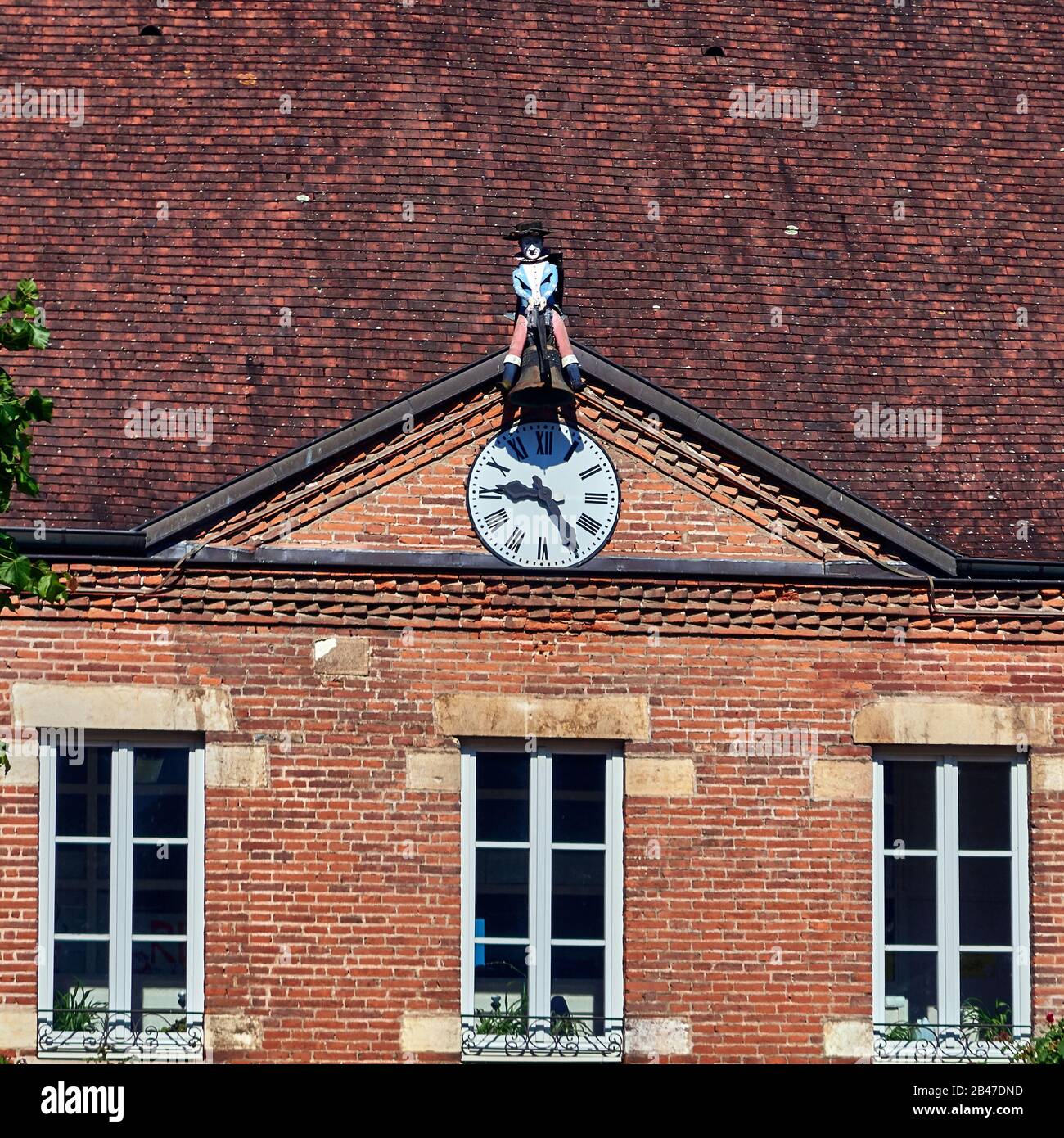 France , Seurre town, Bourgogne-Franche-Comté department, a jacquemart clock on the facade of the girls's school. The jacquemart clock in Seurre is one of the last in France still working. Tjhe automaton's clothes and hat are in French tricolour. It sits astride a beam and holds a hammer linked to the clock by cables which drive it into action. Stock Photo
