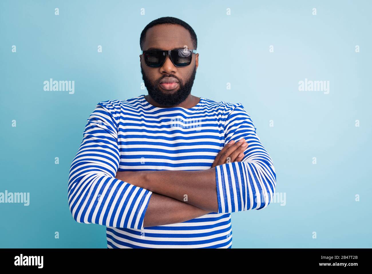Photo of dark skin guy arms crossed not strictly looking travelers sea beach wear sun glasses striped sailor shirt isolated Stock Photo -