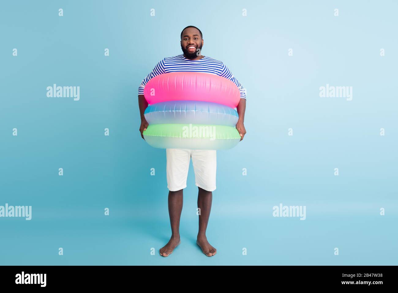 Full size photo of funky funny barefoot afro american guy enjoy weekend  have colorful ring float lifesaver buoy ready swim in ocean wear white  shorts Stock Photo - Alamy