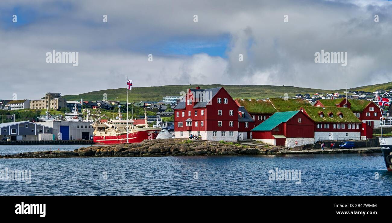 Denmark, Tinganes peninsula , Torshavn, Streymoy, Faroe Islands. Tinganes is the historic location of the Faroese landsstýri (government), and is a central part of Tórshavn. The name Tinganes means 'parliament jetty' or 'parliament point' in Faroese. Many of the wooden houses on Tinganes were built in the 16th and 17th centuries and have the typical red color as well as grass roof, that is very common on the Faroe Islands. Stock Photo