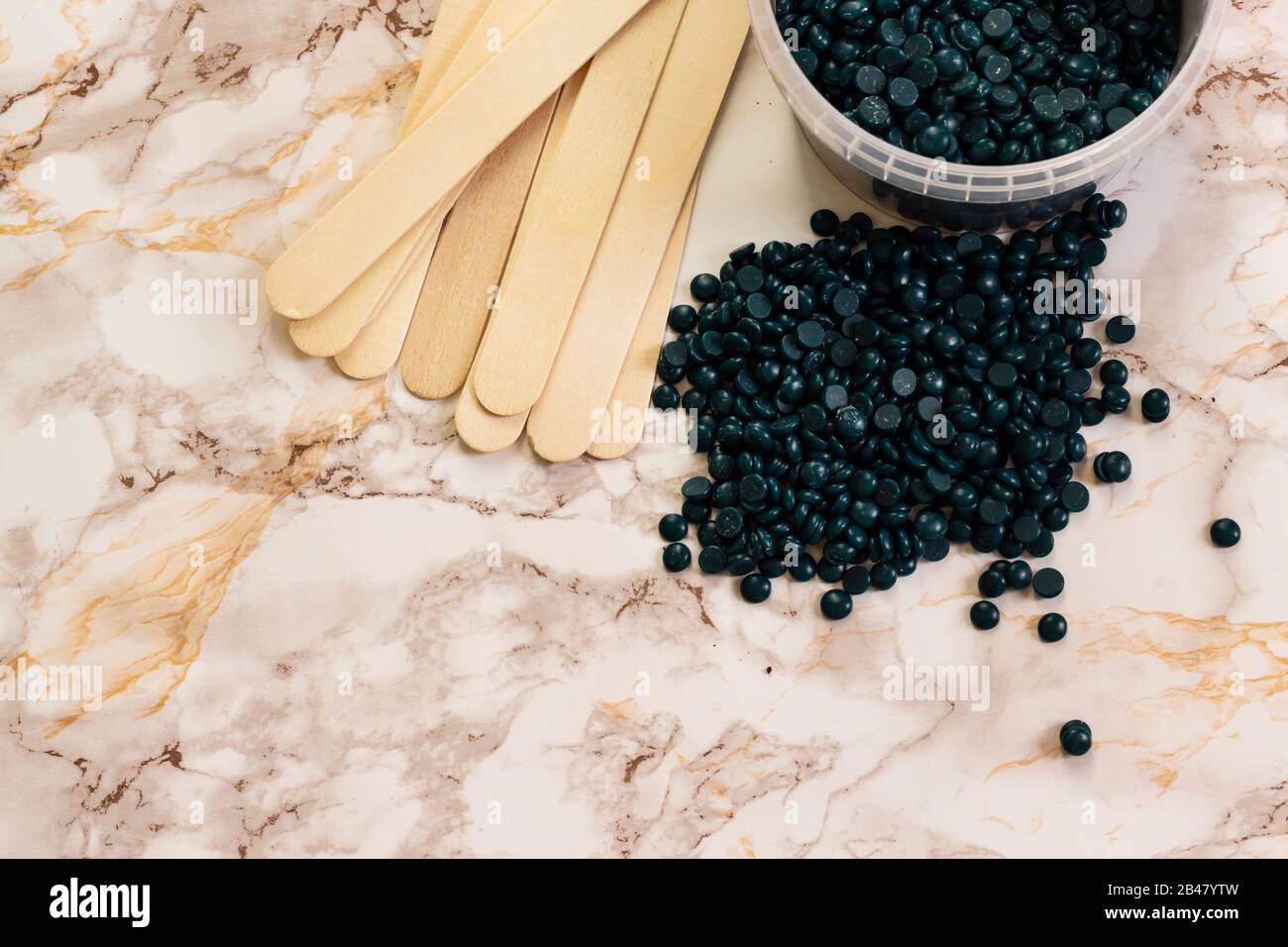 depilatory pearly blue solid wax beans and wooden stick on marble