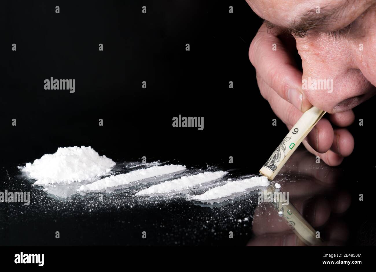 Snorting a line of cocaine. There are three lines on a glass table, and a  pile to the left. A person's nose is snorting through a rolled bill Stock  Photo - Alamy