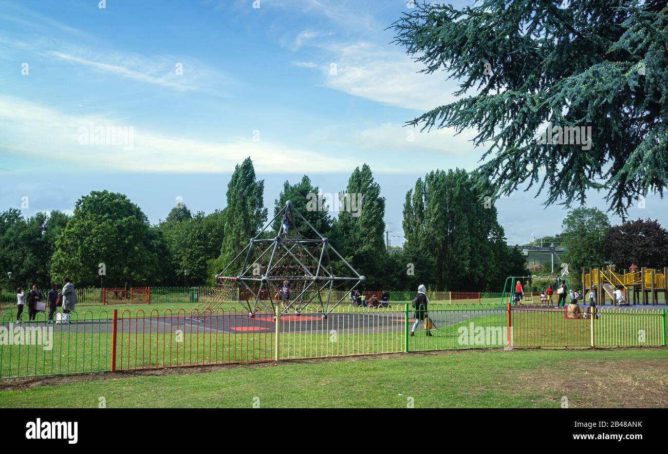 children enjoying the play areas in Salt Hill Park, Slough, whilst their parents look on. Sunny day, mid summer Stock Photo