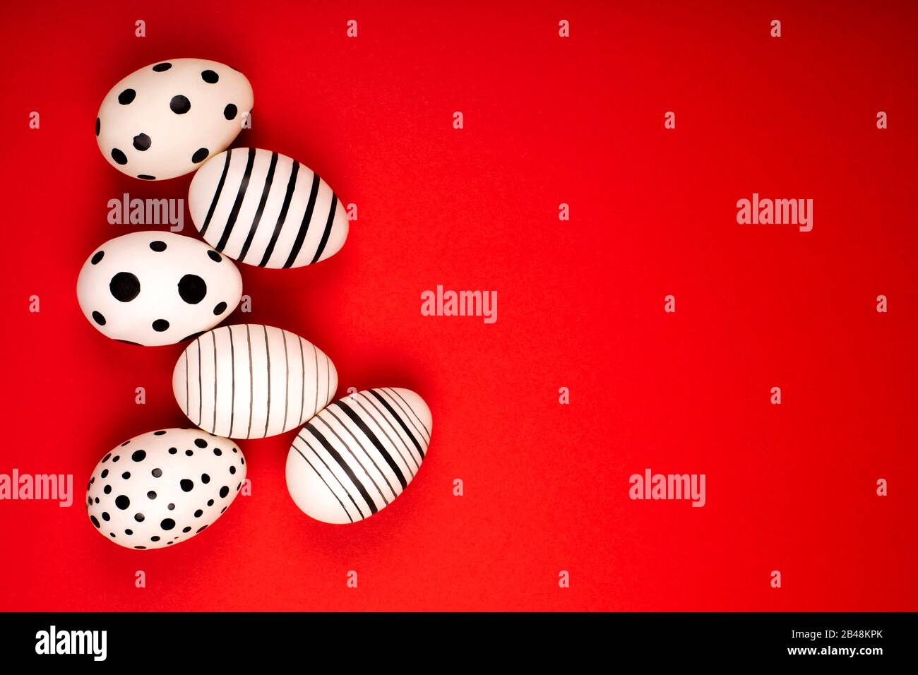 Different graphic hand-painted eggs on bright red background. Easter concept. Place for text. Stock Photo