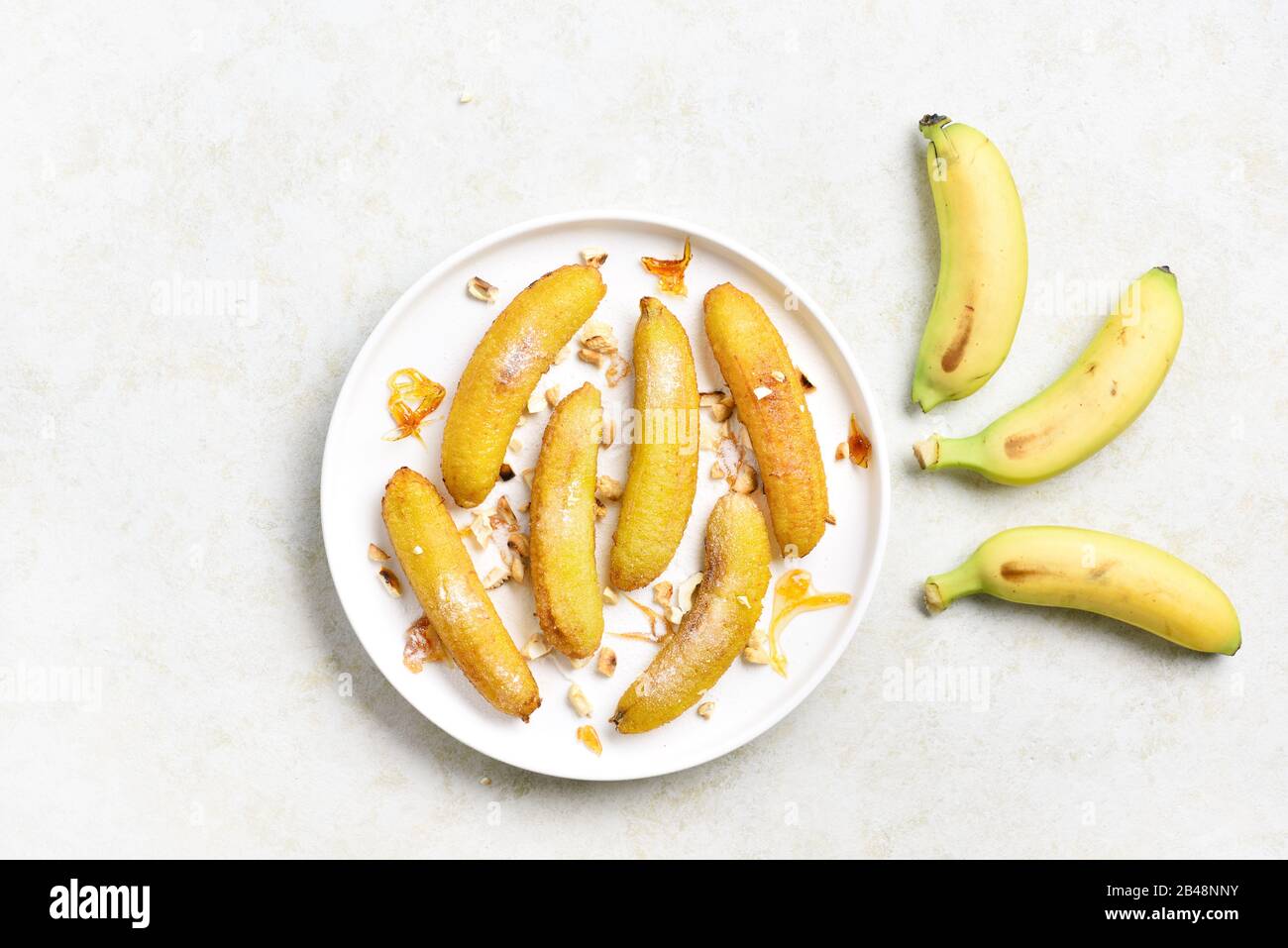 Deep fried bananas on plate over light stone background. Tasty dessert