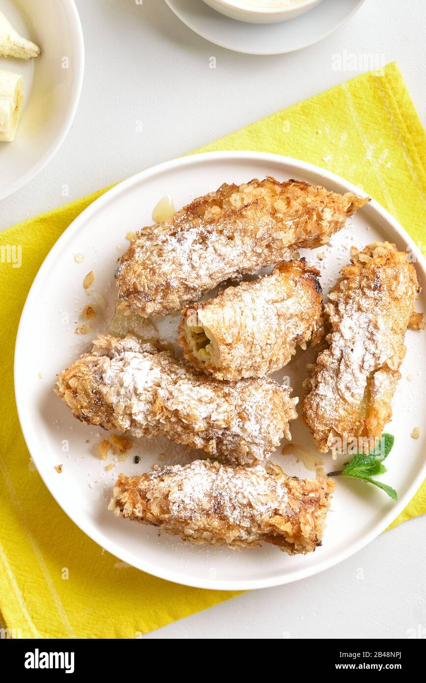 Deep fried bananas on plate over white stone background. Tasty dessert