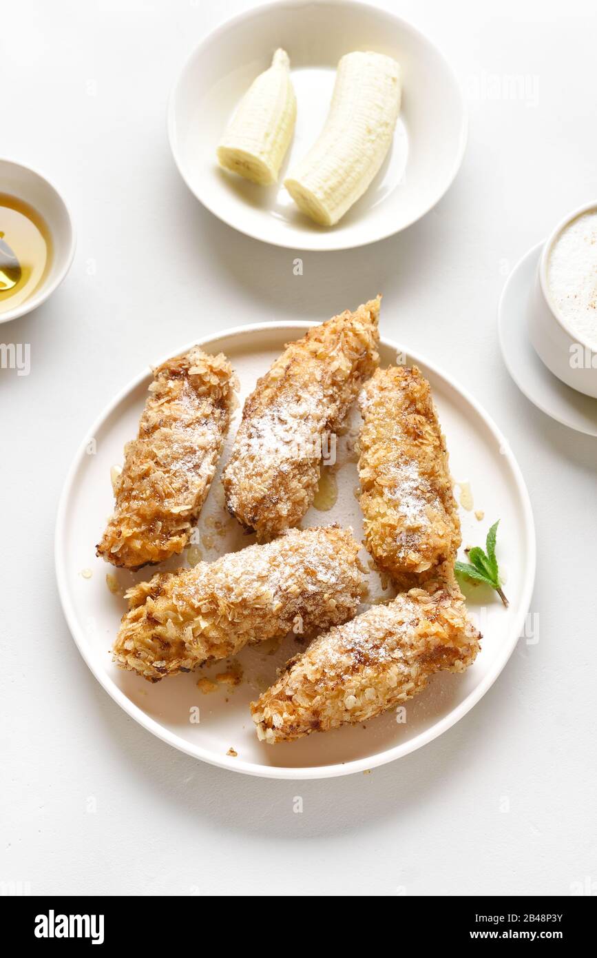 Deep fried bananas on plate over white stone background. Tasty dessert