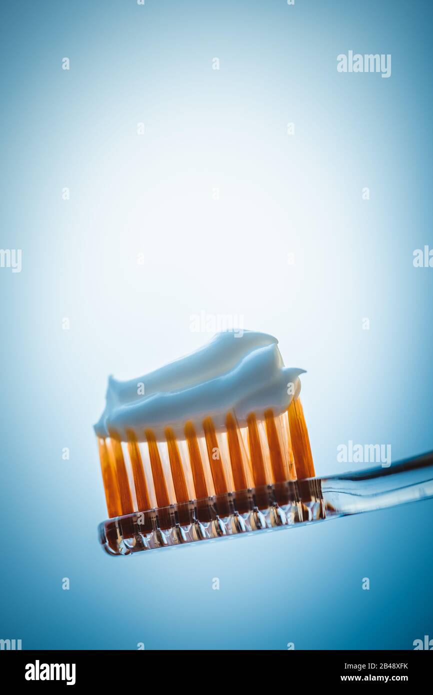 Plastic toothbrush with white toothpaste on a blue background. Stock Photo