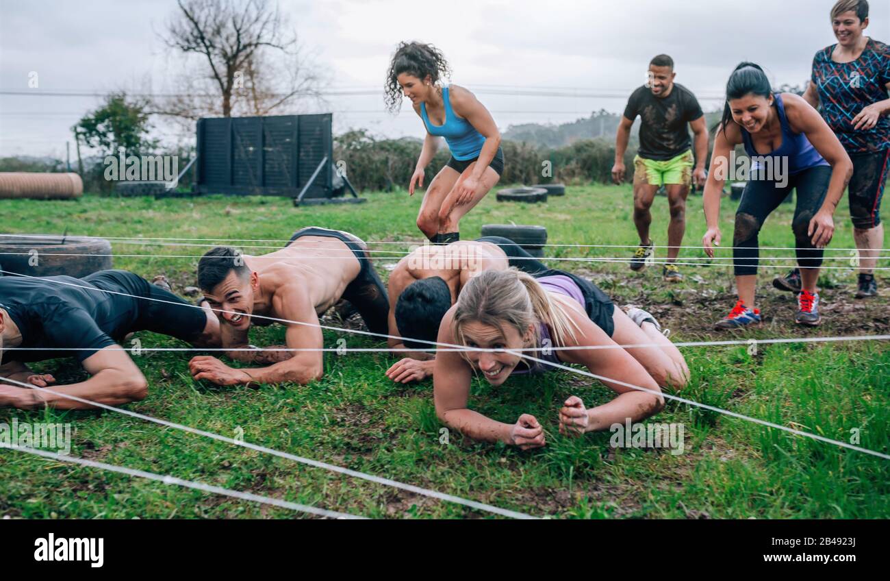 Participants in an obstacle course crawling Stock Photo