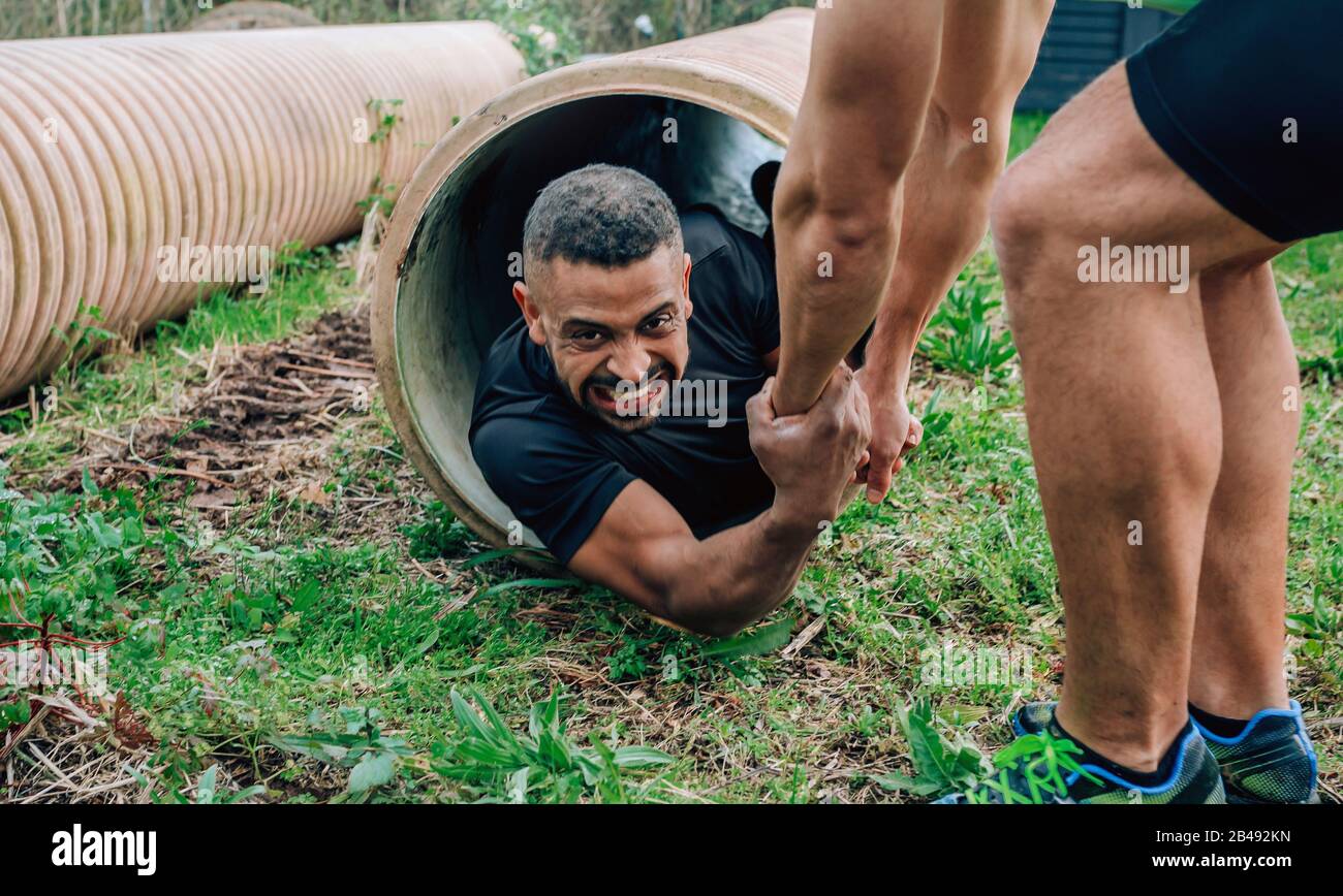 Participants obstacle course going through a pipe Stock Photo