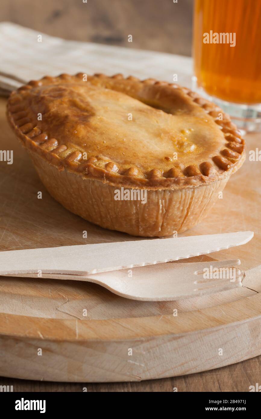 Savoury meat or steak pie with a golden oven baked crust and a glass of beer Stock Photo