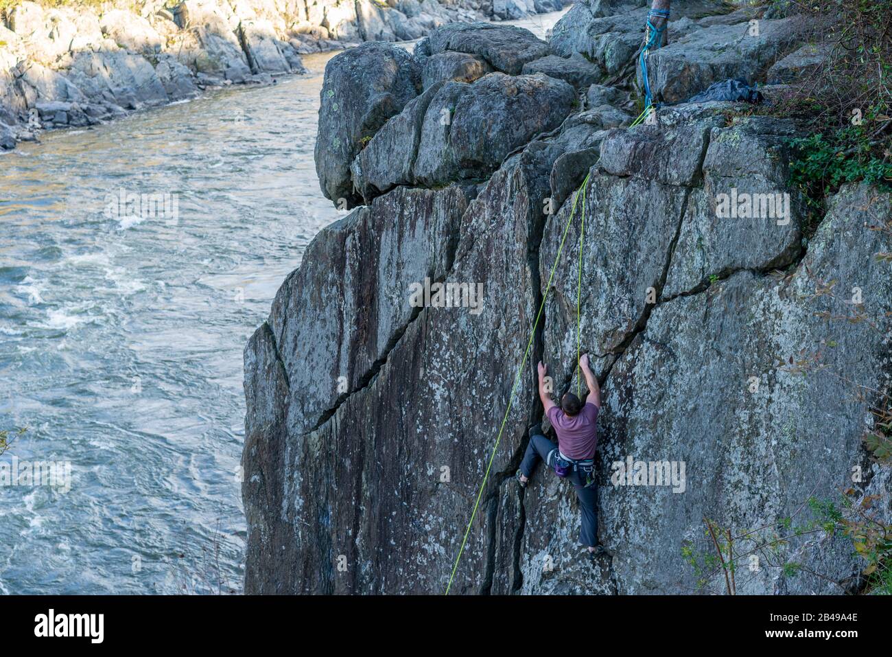 Climber scaling a rock wall in Great Falls Park, Maryland. Overlooking