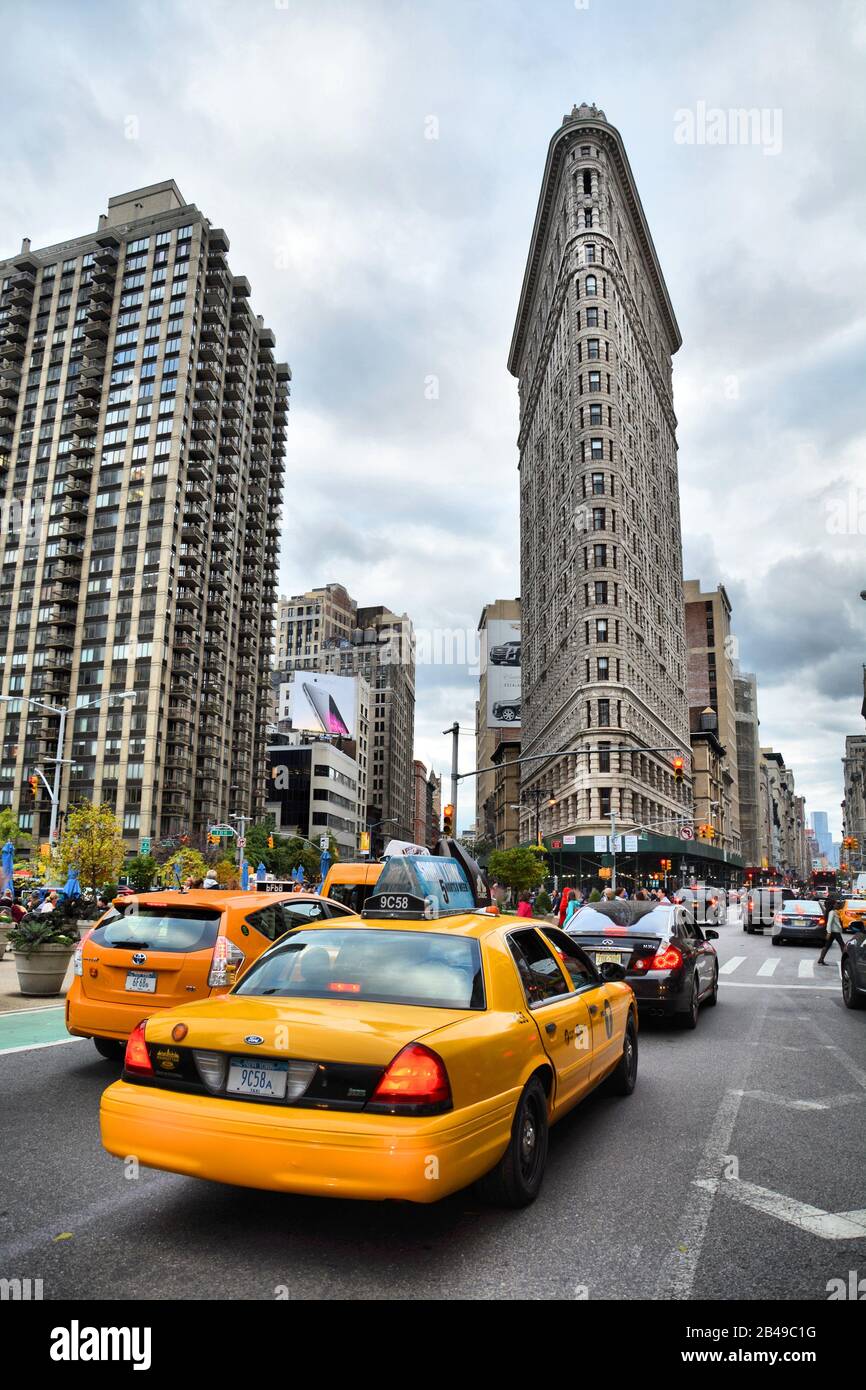 NEW YORK CITY, USA - OCTOBER 18, 2014: Yellow taxi and Flatiron building at Fifth Avenue av in Manhattan. Flatiron is an iconic buiding of NYC. Stock Photo