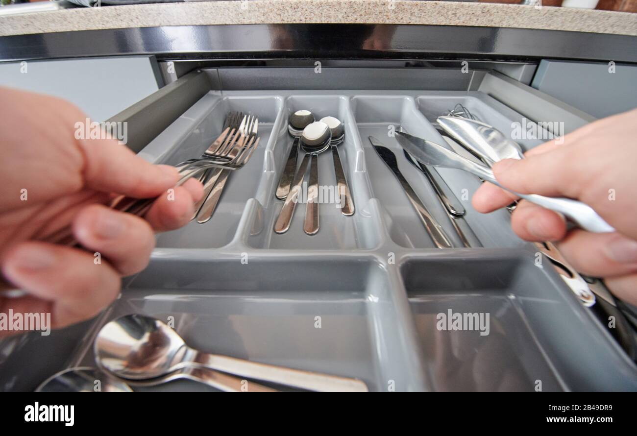 Organizing kitchen cutlery to plastic drawer close up view Stock Photo