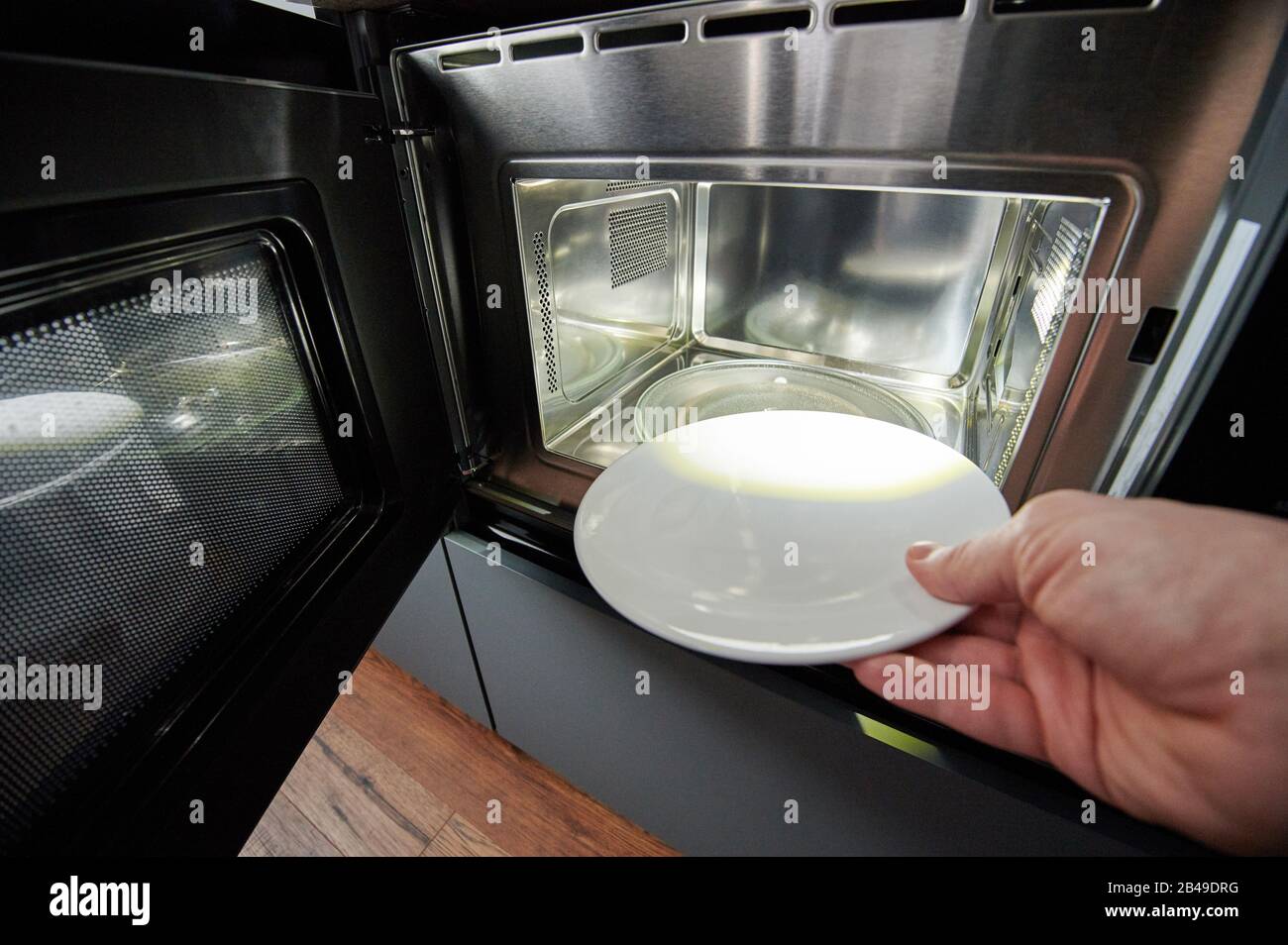 Hand putting empty plate in microwave close up view Stock Photo Alamy
