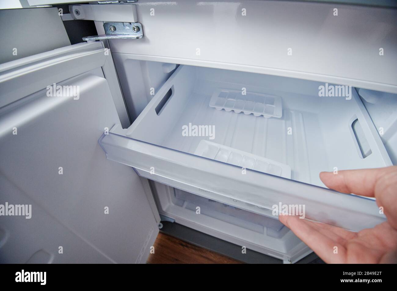 Open clean fridge freezer container with ice cubes Stock Photo