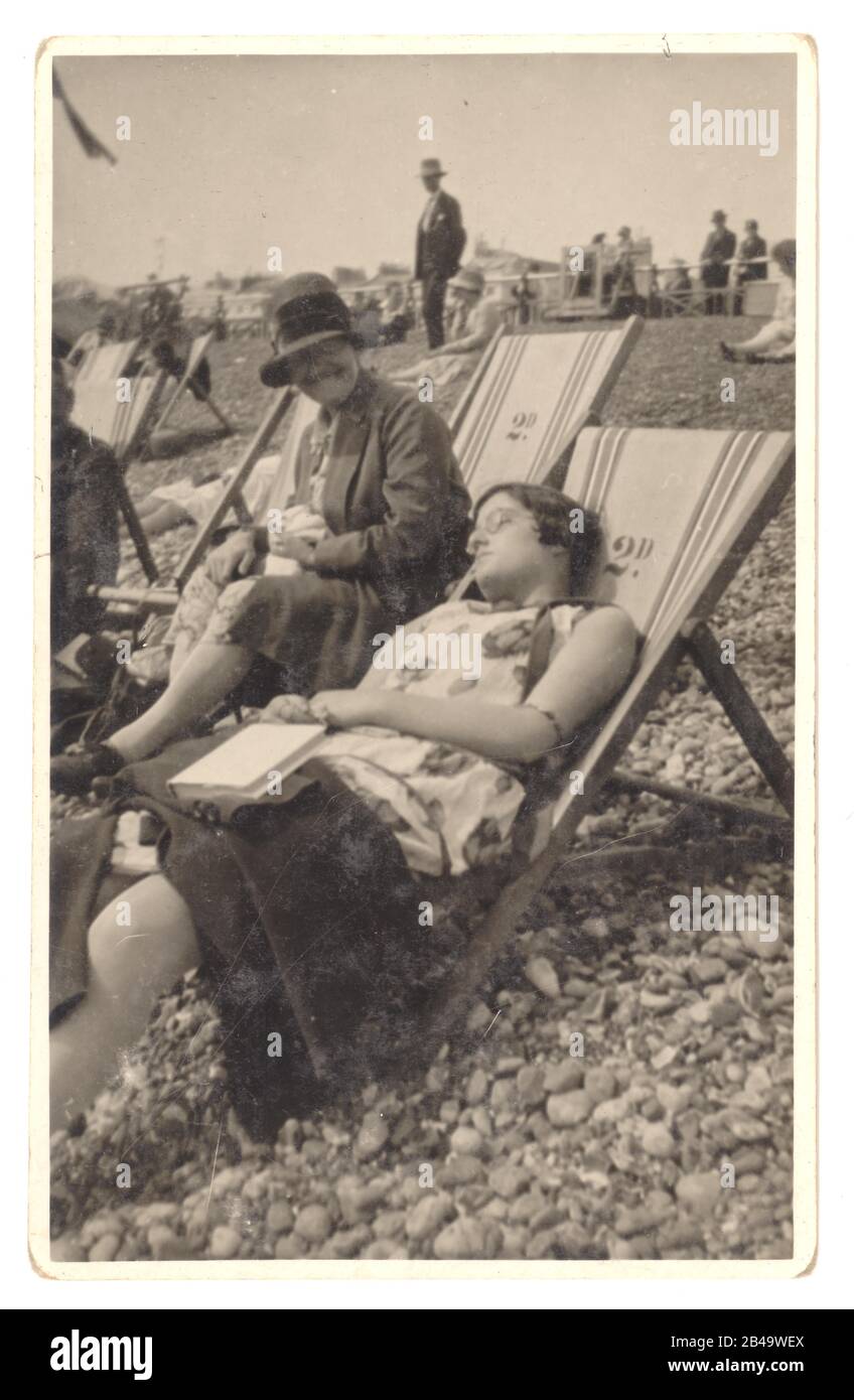 Early 1920's candid photo of women in deckchairs, one asleep, the other laughing at her friend.  On the reverse of the postcard is written 'August 1928, Brighton' Brighton, Sussex, England, U.K. Stock Photo