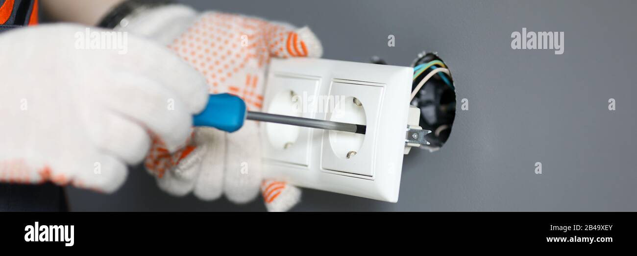Repairman in gloves fixing socket with screwdriver Stock Photo