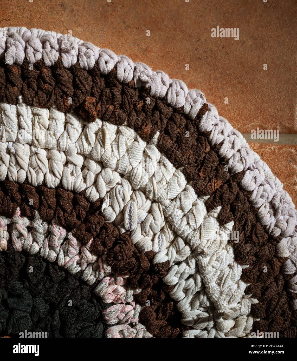 white  brown and black rag rug made from tshirt thread. on tiled floor. Stock Photo