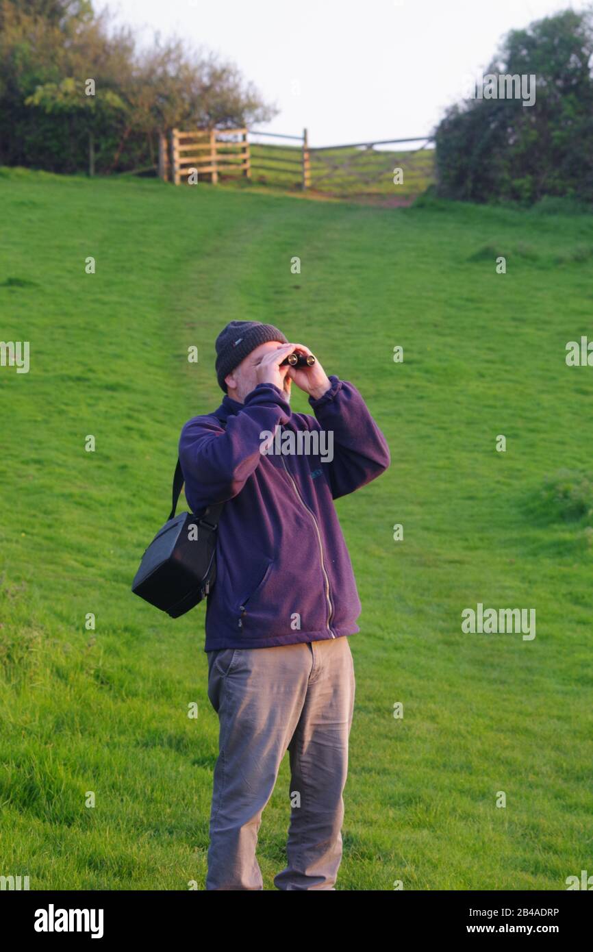 60 Year Old Man, Birdwatching with Binoculars on a Sunny Spring Day