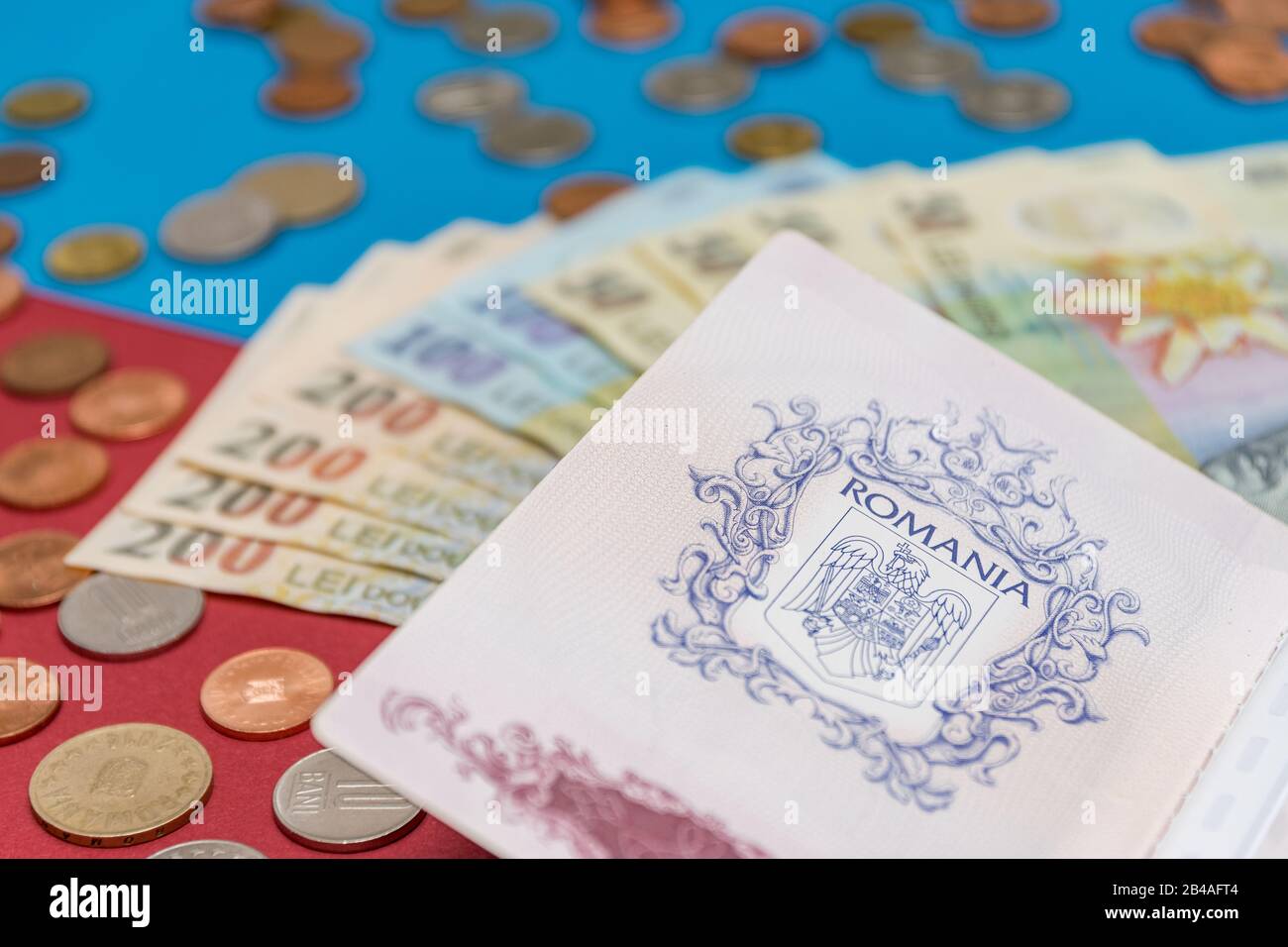 Romanian concept. The Romanian passport and Romanian banknotes/coins on a blue and red background. Coloseup of Romanian Passport and Romanian currency Stock Photo