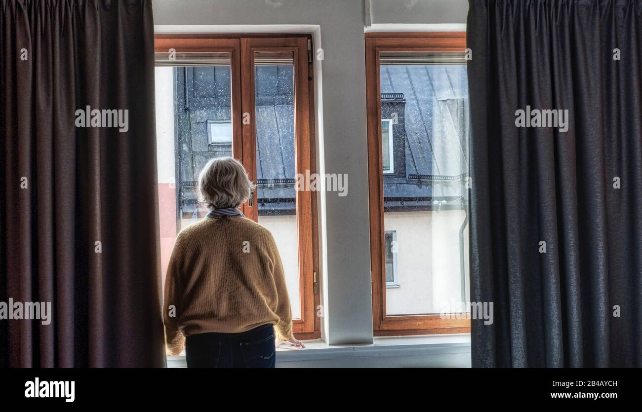 Middle aged woman looking out the windows Stock Photo