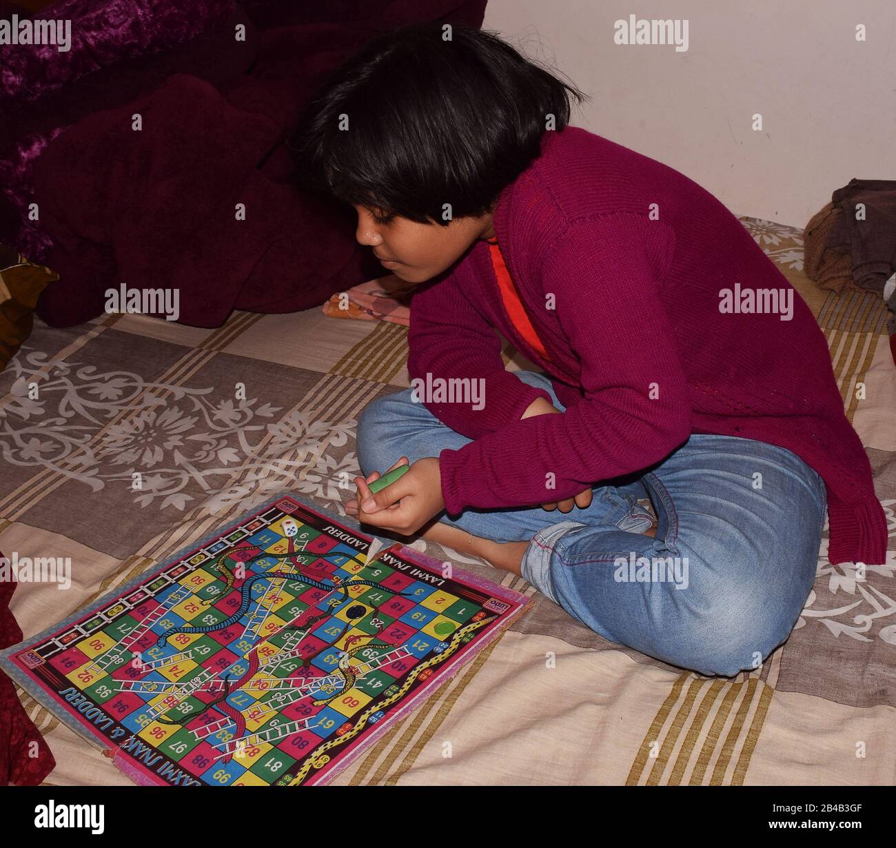 A child playing Ludo game. Ludo is a strategy board game for two to  four players and played with a Dice Stock Photo