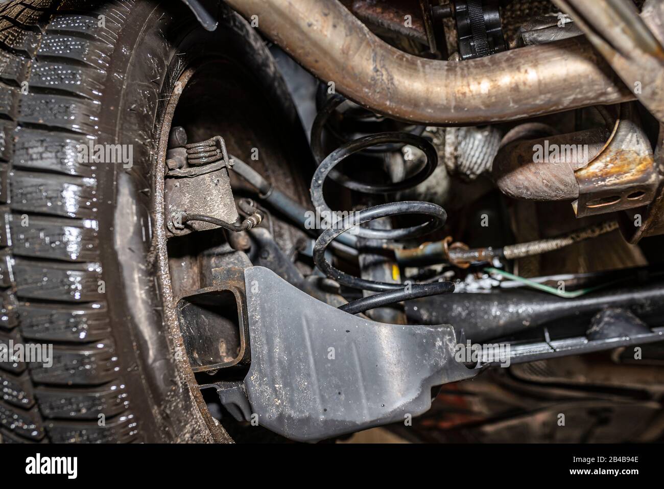 Rear car suspension from below, visible suspension springs, shock