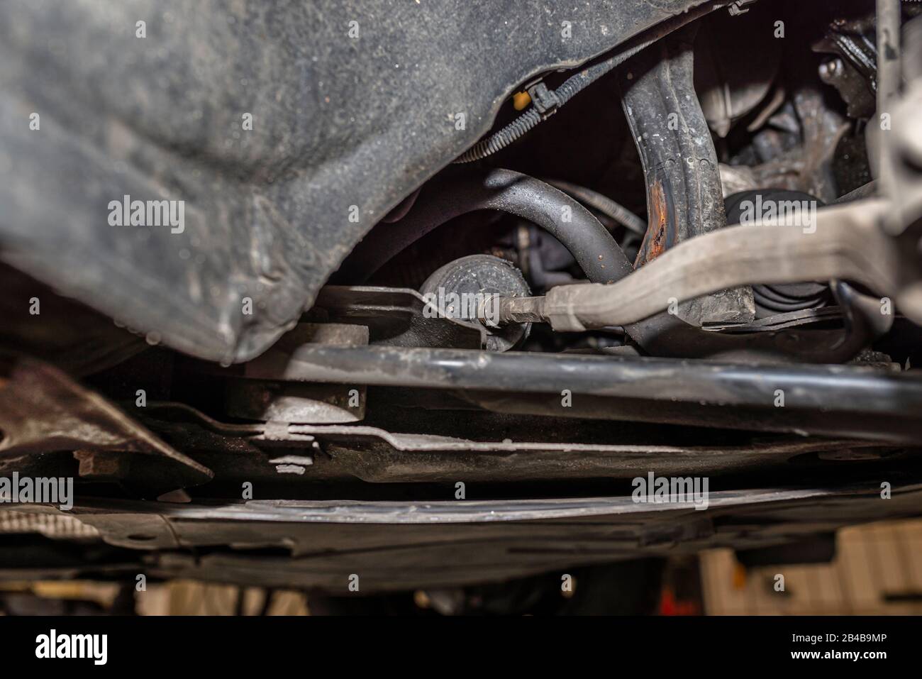 Steering stabilizer connected with steering knuckle, seen from the bottom of the car on a jack in the workshop. Stock Photo