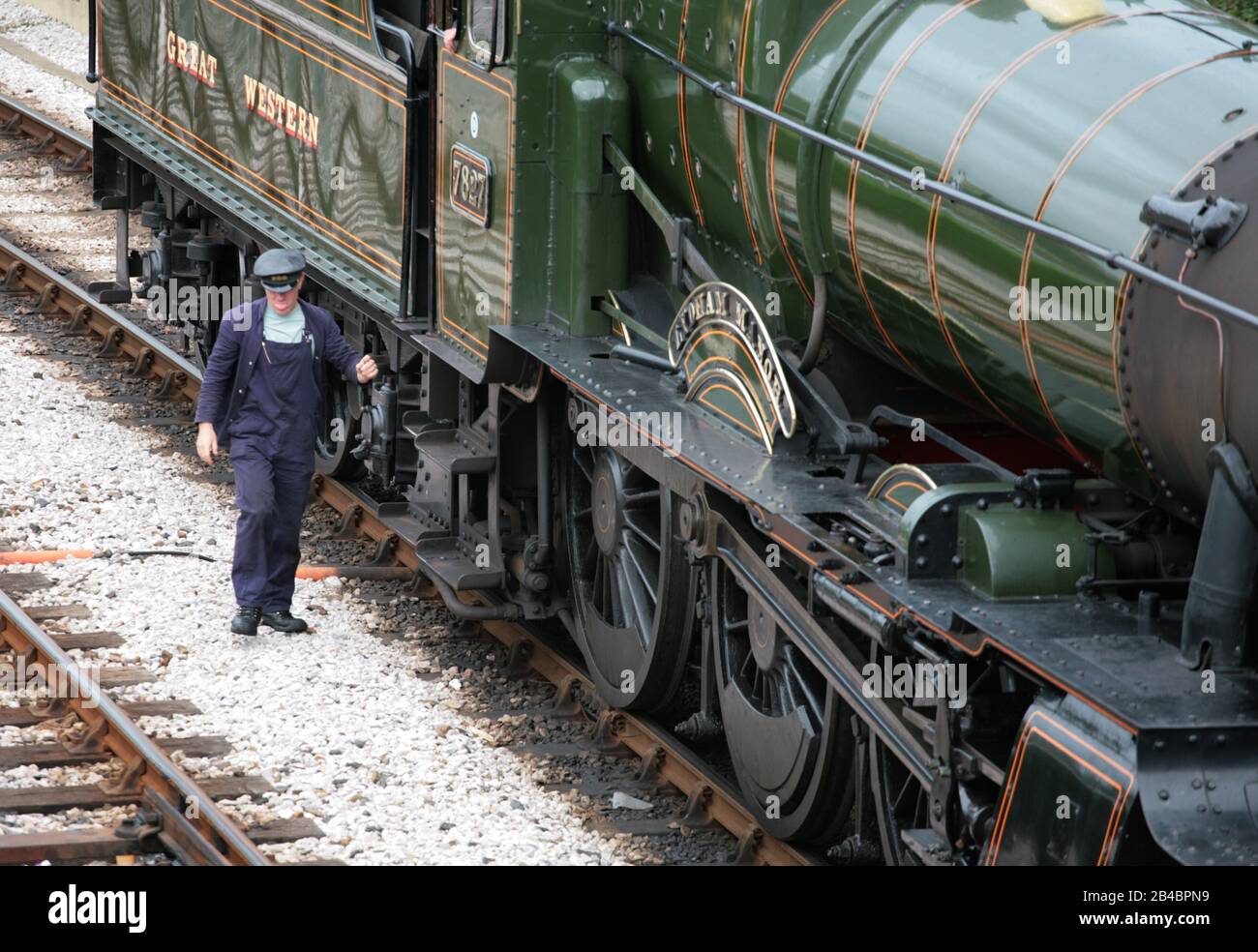 GWR 'Manor' class locomotive No. 7827 'Lydham Manor' at Kingswear Station on the Dartmouth Steam Railway: fireman alights from the cab: Devon, England Stock Photo