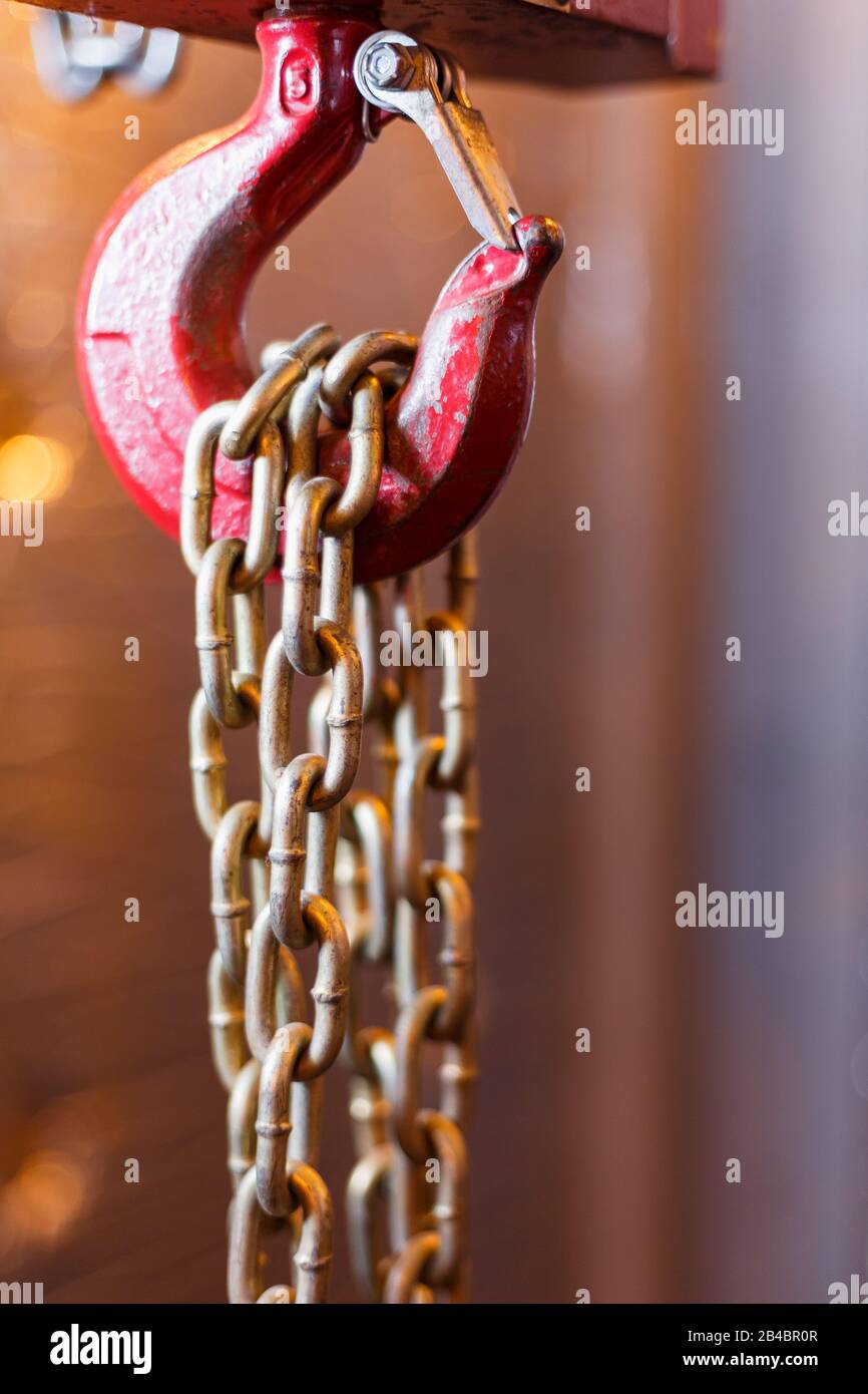 metallic chain handle with red hook in technical room. Crane cargo hook. Concept of maintenance and construction work. Stock Photo