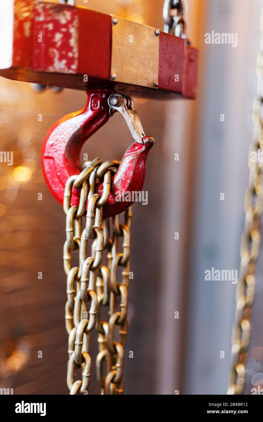 metallic chain handle with red hook in technical room. Crane cargo hook. Concept of maintenance and construction work. Stock Photo