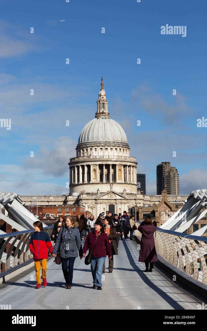 UK tourism; tourists crossing the Millennium Bridge in front of St Pauls Cathedral on a sunny day in March, London city centre, London  UK Stock Photo