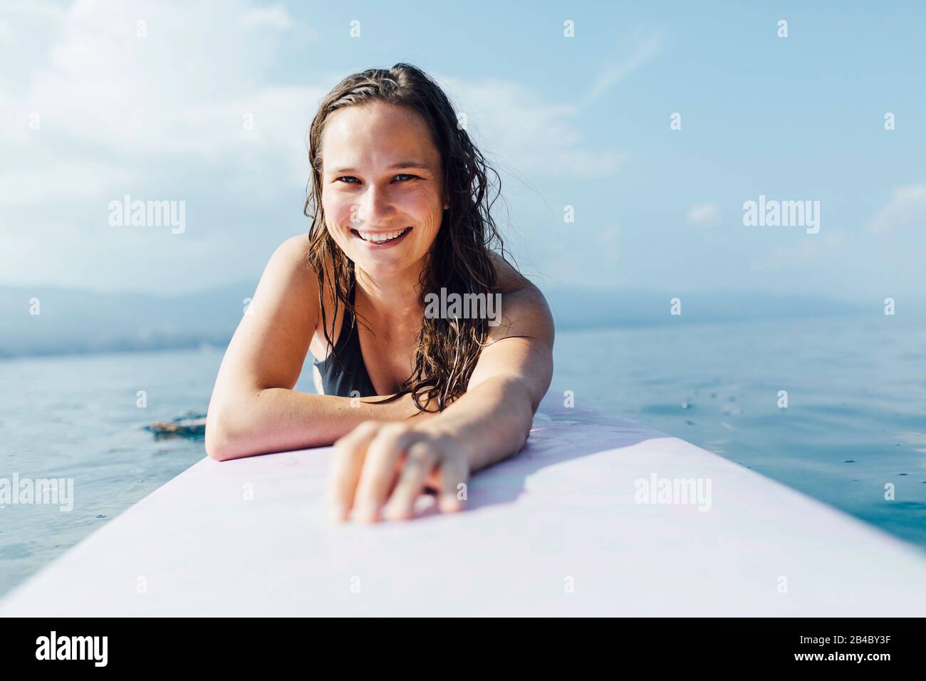 Junge Frau 20-30 Jahre liegt auf Surfbrett und genießt die Sonne, Kroatien Stock Photo