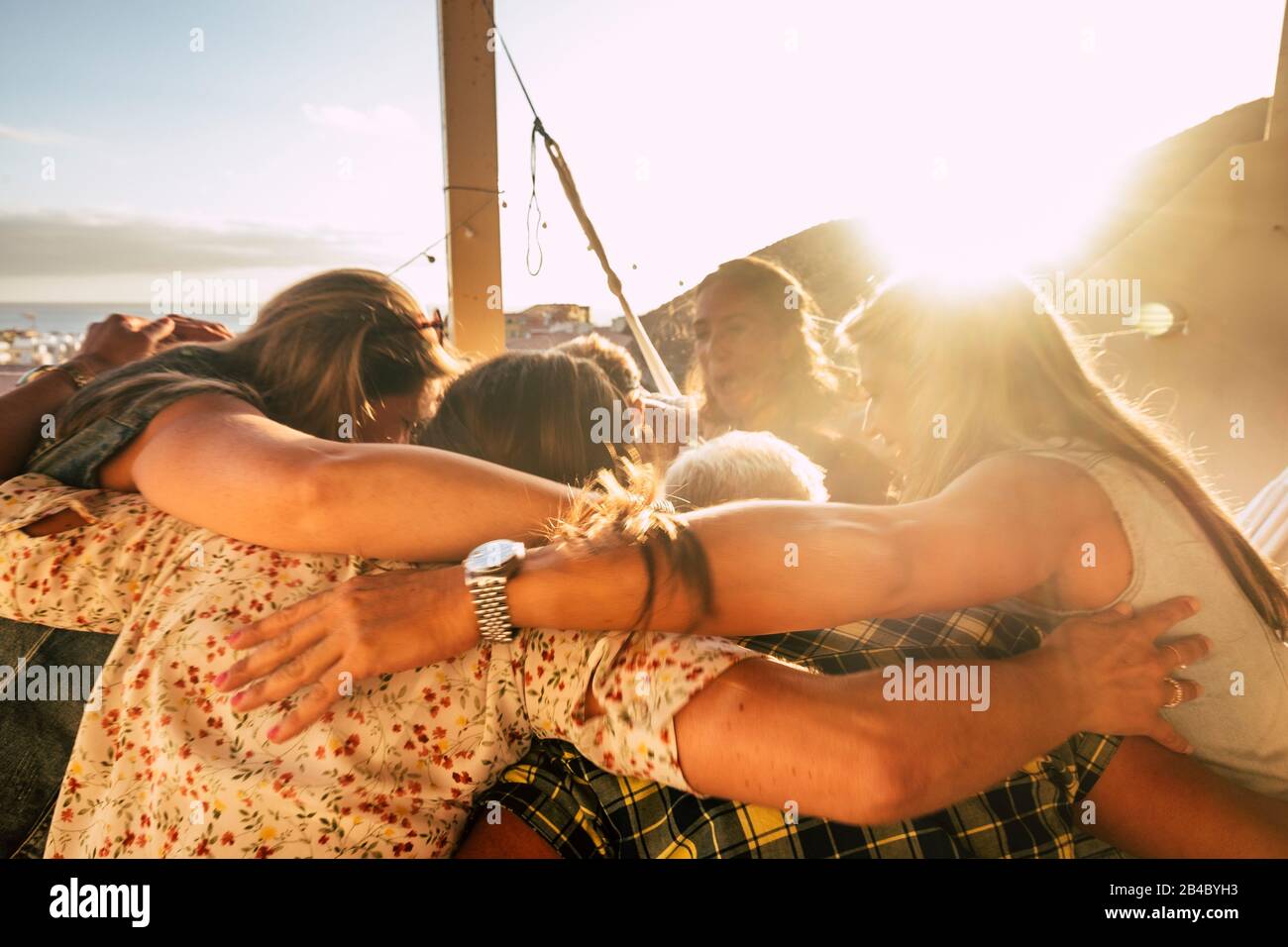 Teamwork and friendship concept for people outdoor hugging all together with love and friends lifestyle - happiness and relationship with group of females having fun - ocean view Stock Photo