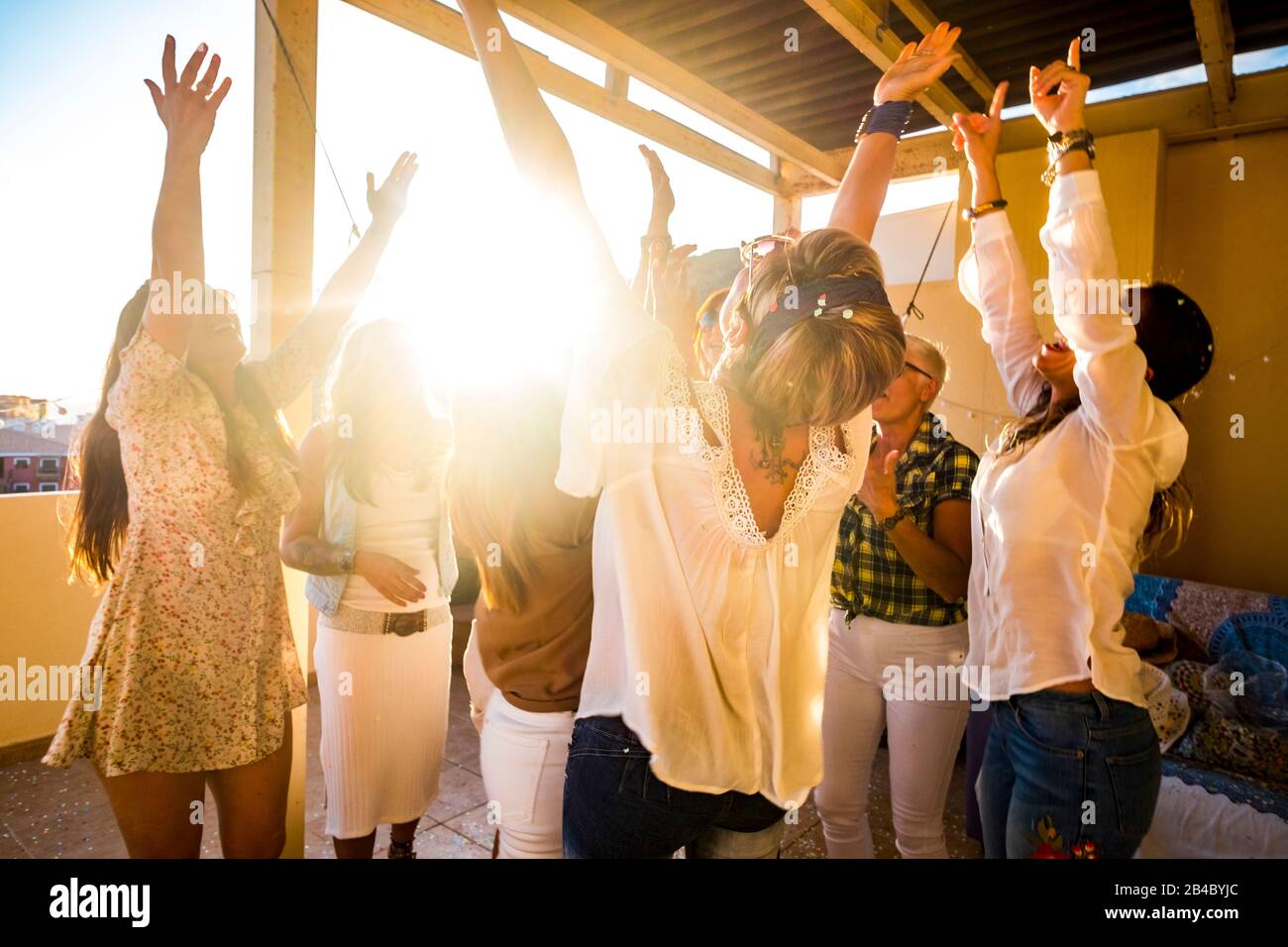 Active happy group of young free caucasian people woman celebrate and dance all together with friendship - sunset in backlight for party at home concept - Happiness for group Stock Photo
