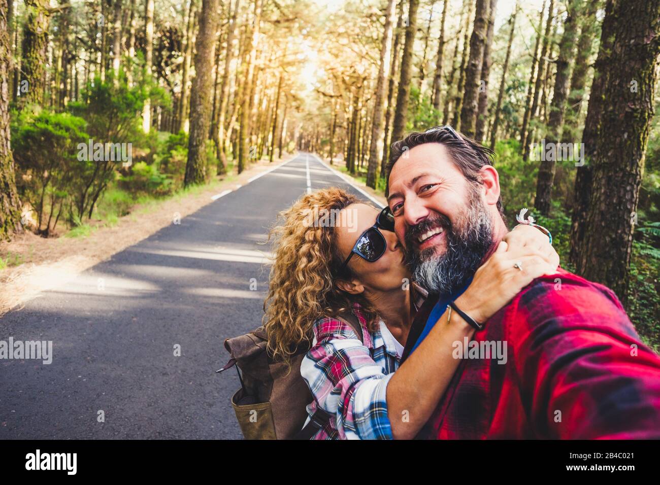 Travel people outdoor concept with happy couple caucasian man and woman hug and kiss  with love - relationship and vacation on mountain forest for cheerful adults - enjoying and happiness lifestyle for hipsters Stock Photo