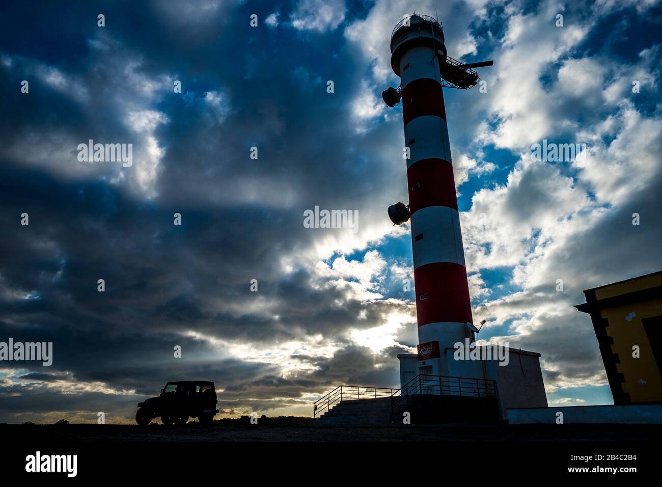 Beautiful sunset sky with clouds and lighthouse on the coast line - off road adventure car vehicle parked there. concept of wild trafvel alternative vacation or exploring world - outdoor nature scenic place Stock Photo
