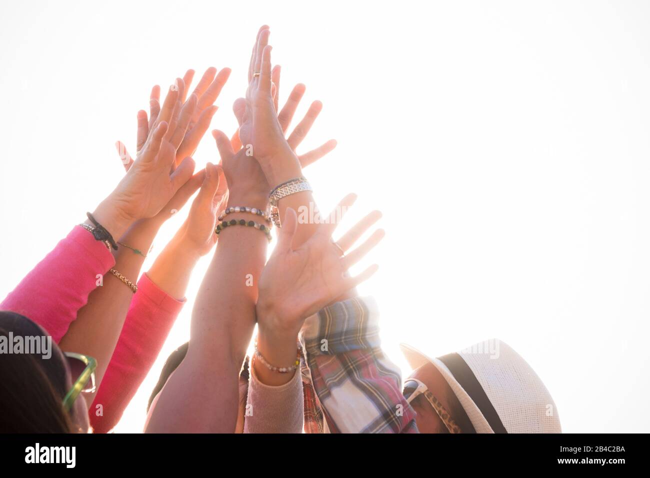 group of hands and arms up with the white sky at the background - teamwork of womens enjoying and having fun together celebrating something  with happiness Stock Photo