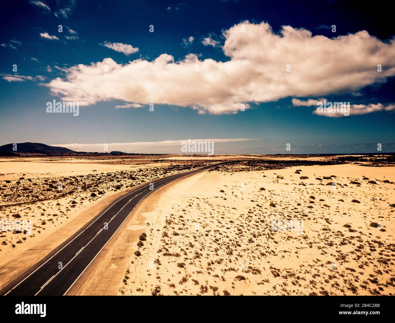 Long black asphalt road in the middle of the desert with nature and outdoors around - concept of travel and adventure in alternative beautiful senic place - aerial view Stock Photo