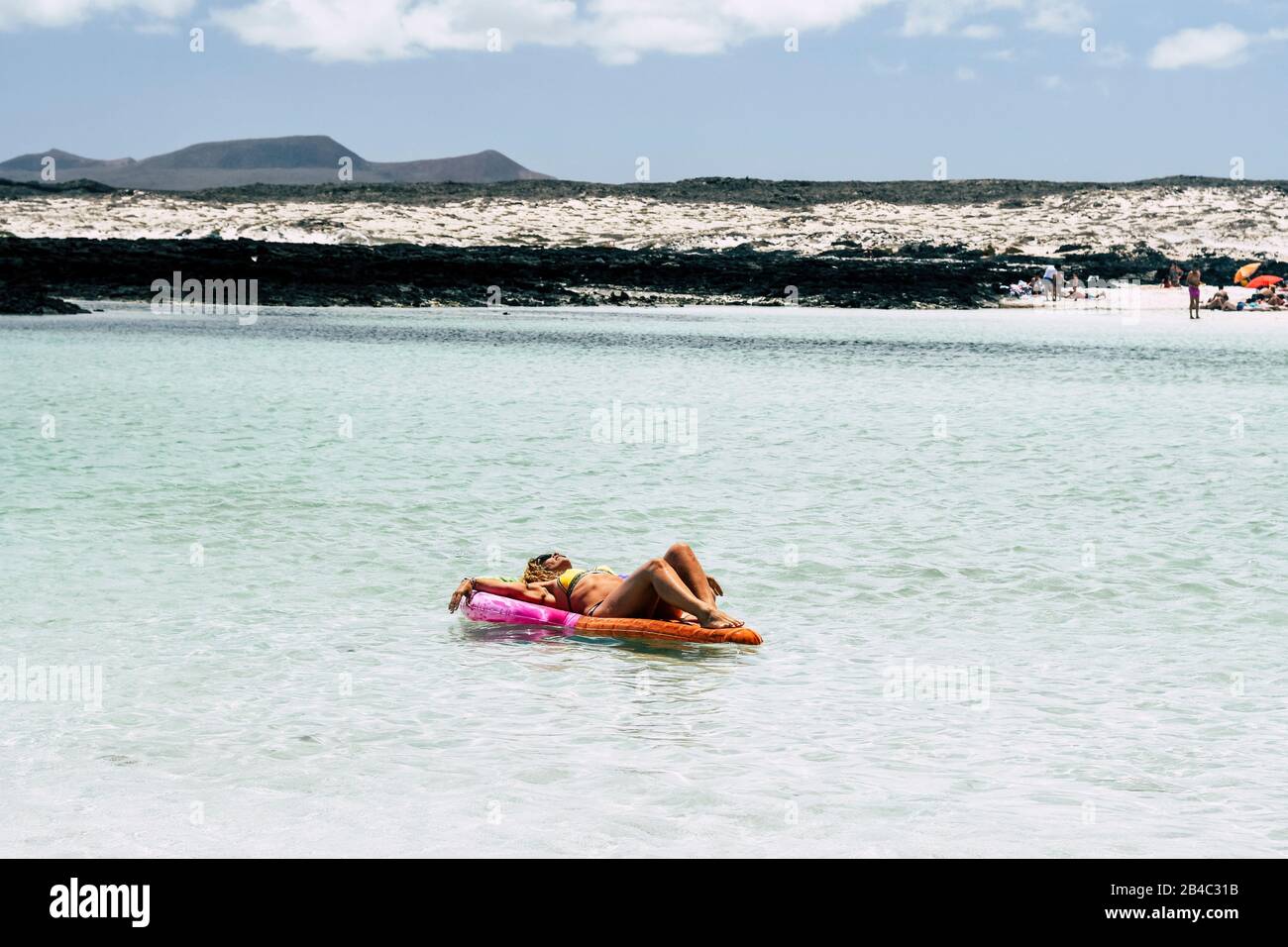 Tourism and travel lifestyle - beautiful body caucasian woman on a coloured trendy lilo enjoy the sun and the summer vacation relaxing in the transparent caribbean water of ocean Stock Photo