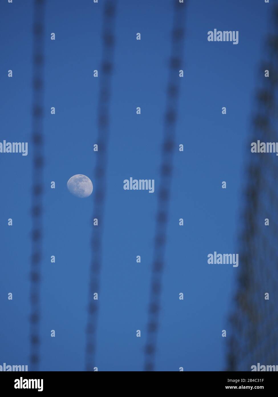 Sheerness, Kent, UK. 6th Mar, 2020. UK Weather: a waxing gibbous moon set against clear blue skies above Sheerness in Kent, seen through the razor wires of a security fence. Credit: James Bell/Alamy Live News Stock Photo