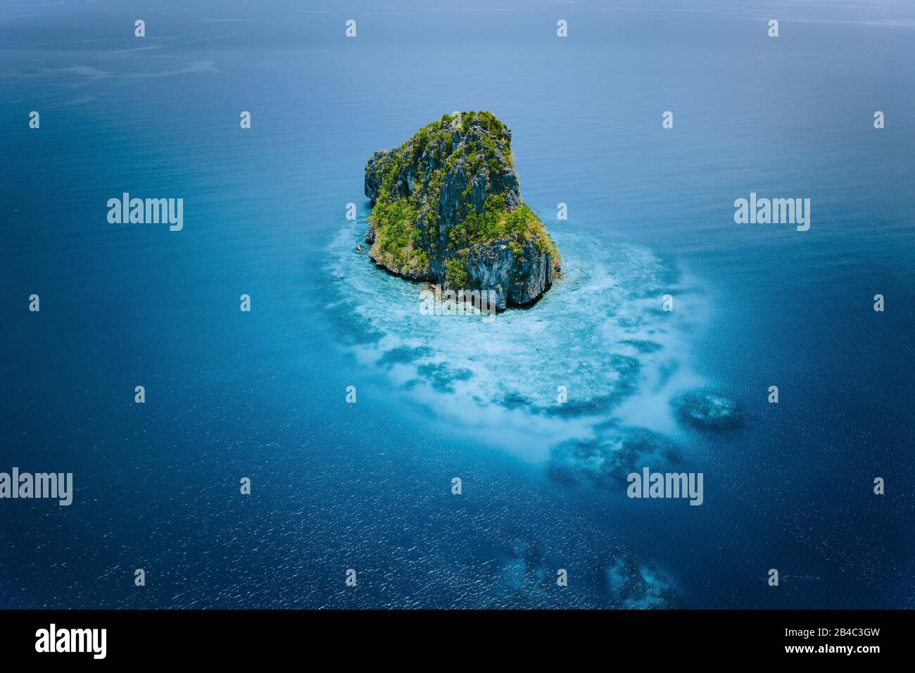 Aerial drone view of a beautiful secluded cliff island surrounded by azure turquoise blue ocean water. Bacuit archipelago is one of the best places for diving. El Nido, Palawan. Stock Photo