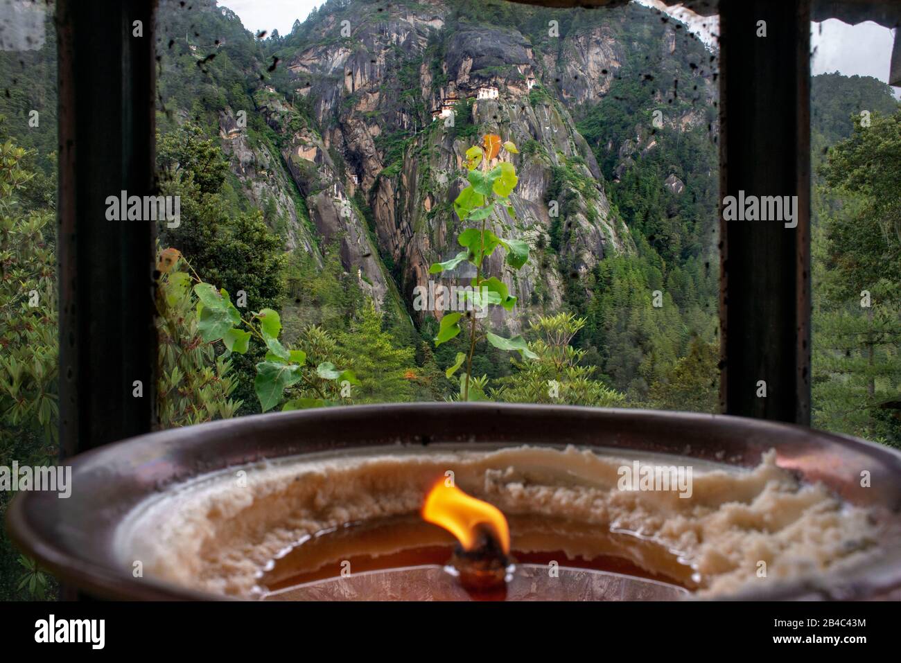 Butter lamps offered by pilgrims situated at the foot of the mountain beneath the Taktsang Goemba or Tigers nest monastery in Paro valley, Bhutan, Asi Stock Photo