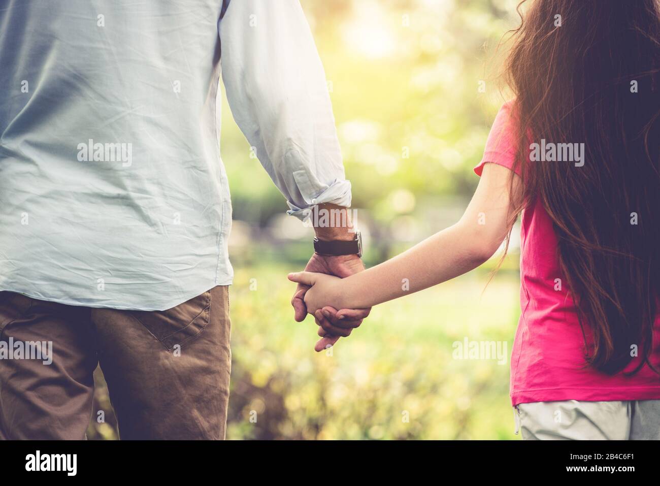 Father and daughter holding hands and walking in the park in summer ...
